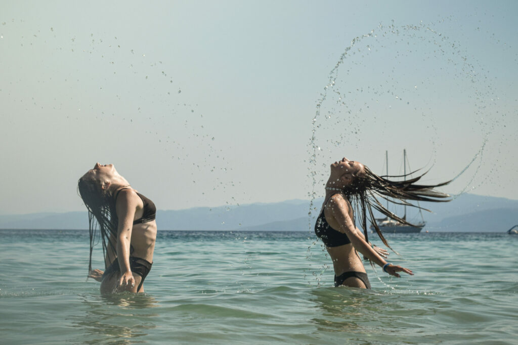 Dwie dziewczyny w morzu Egejskim pozują zarzucając mokrymi włosami