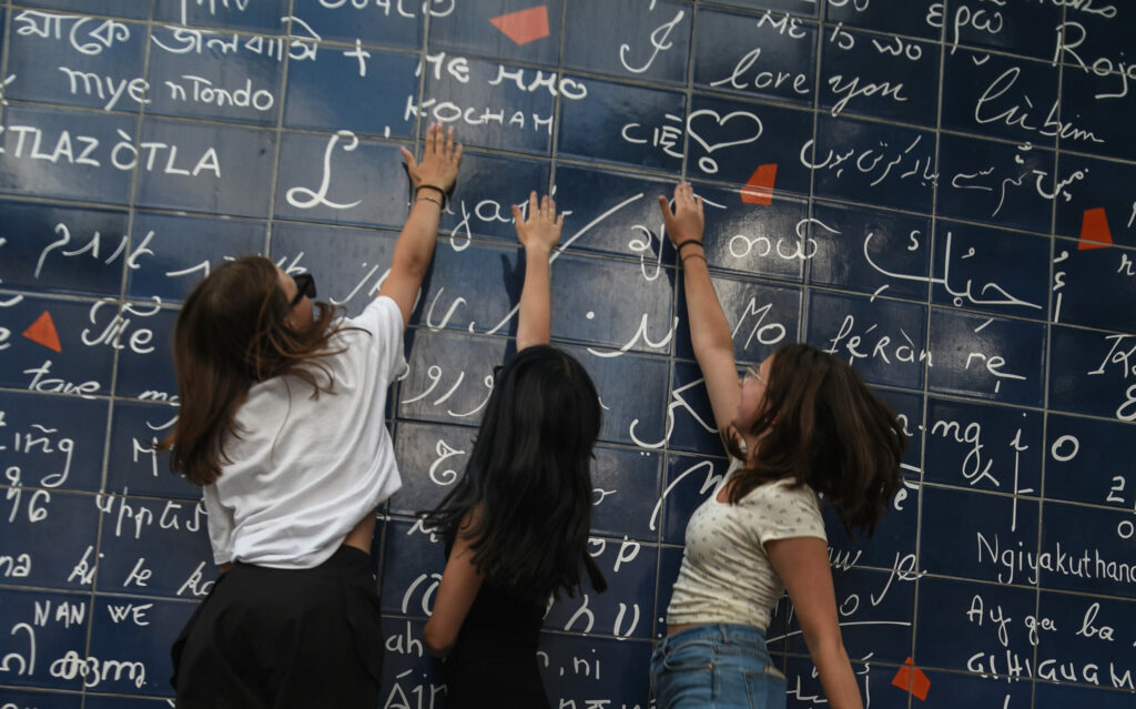 Trzy dziewczyny skaczące przy Le mur des J'aime w dzielnicy Montmartre