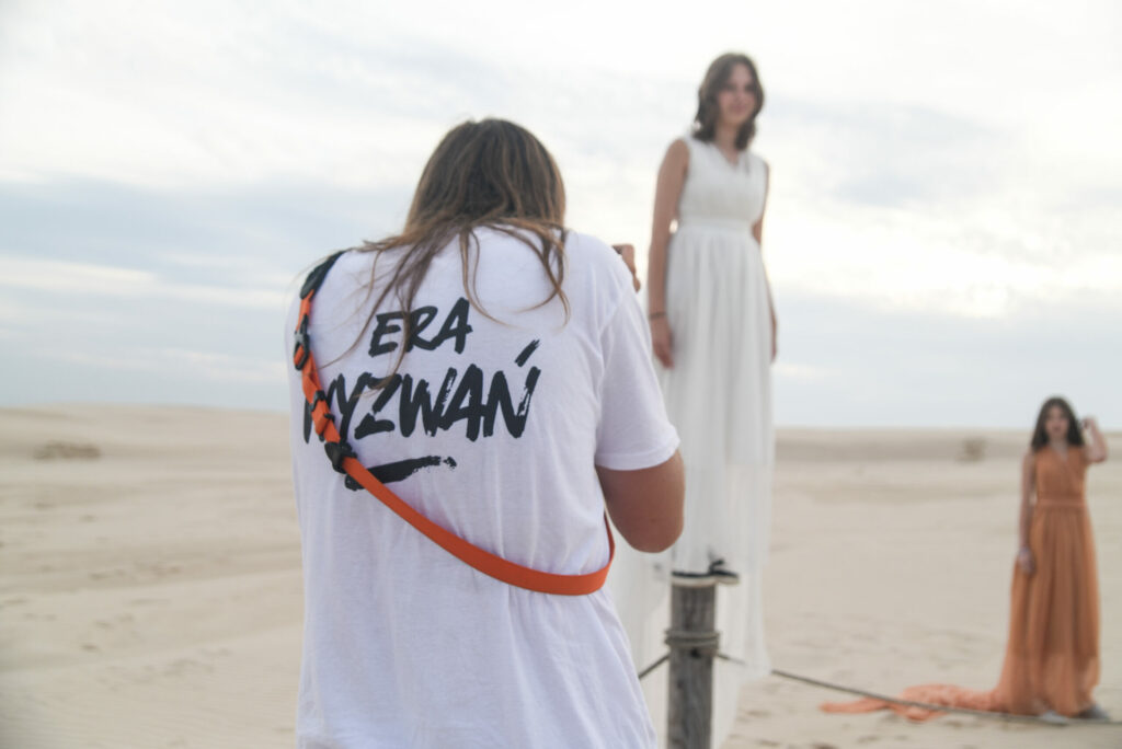 Fotograf podczas warsztatów fotograficznych robiący zdjęcia uczestniczką obozu młodzieżowego nad morzem