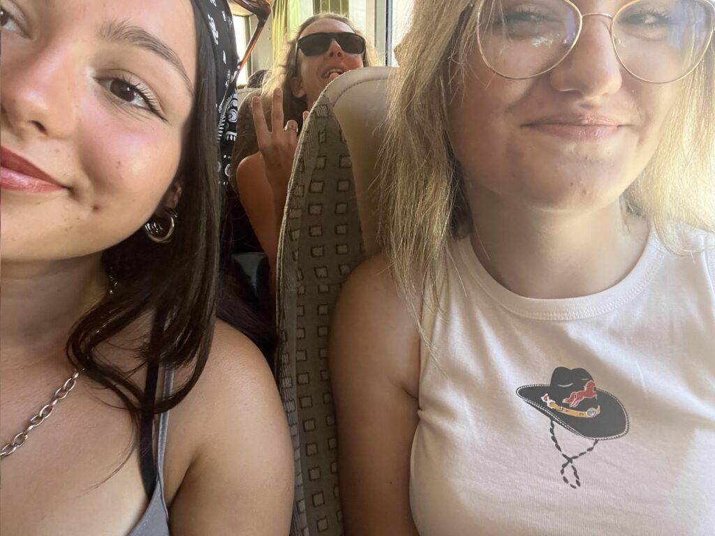 Dwie uśmiechnięte uczestniczki obozu młodzieżowego z Erą Wyzwań siedzące w autokarze