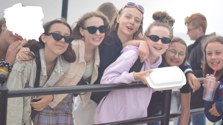 Uśmiechnięta grupa uczestników obozu młodzieżowego nad morzem podczas wycieczki do Międzyzdrojów