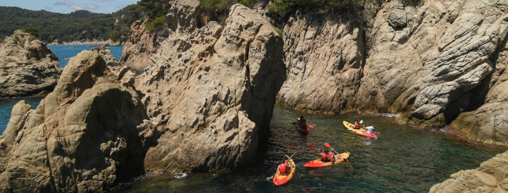 Uczestnicy Ery Wyzwań płynący na kajakach po morzu na plażę de sa Boadella